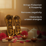 Decorative setting with gold sandals, candles, and flowers on a wooden surface.
