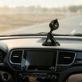 Decorative figurine on a car dashboard with a blurred road.