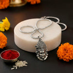 Silver necklace with a detailed pendant on a dark surface.