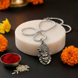 Silver necklace with a detailed pendant on a dark surface.