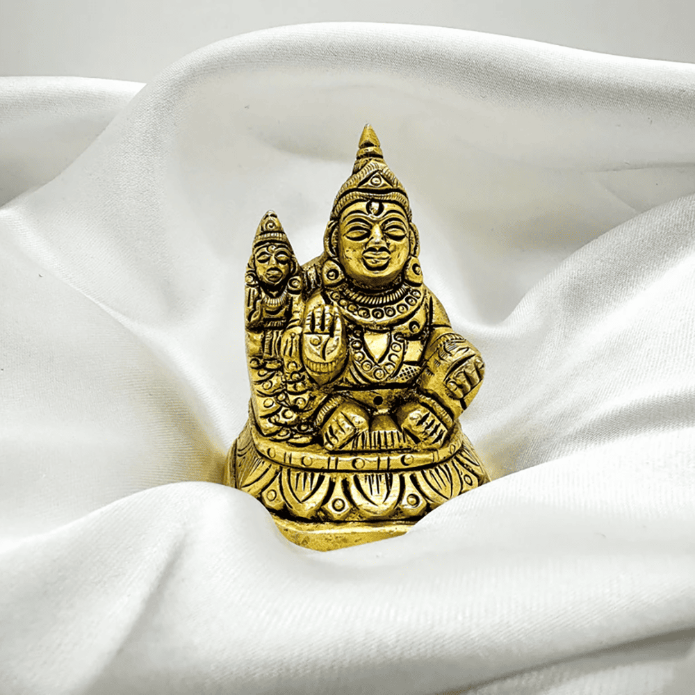 Gold-colored statue of a deity on a white fabric background