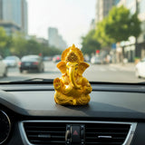 Gold figurine of a deity on a car dashboard with a cityscape in the background