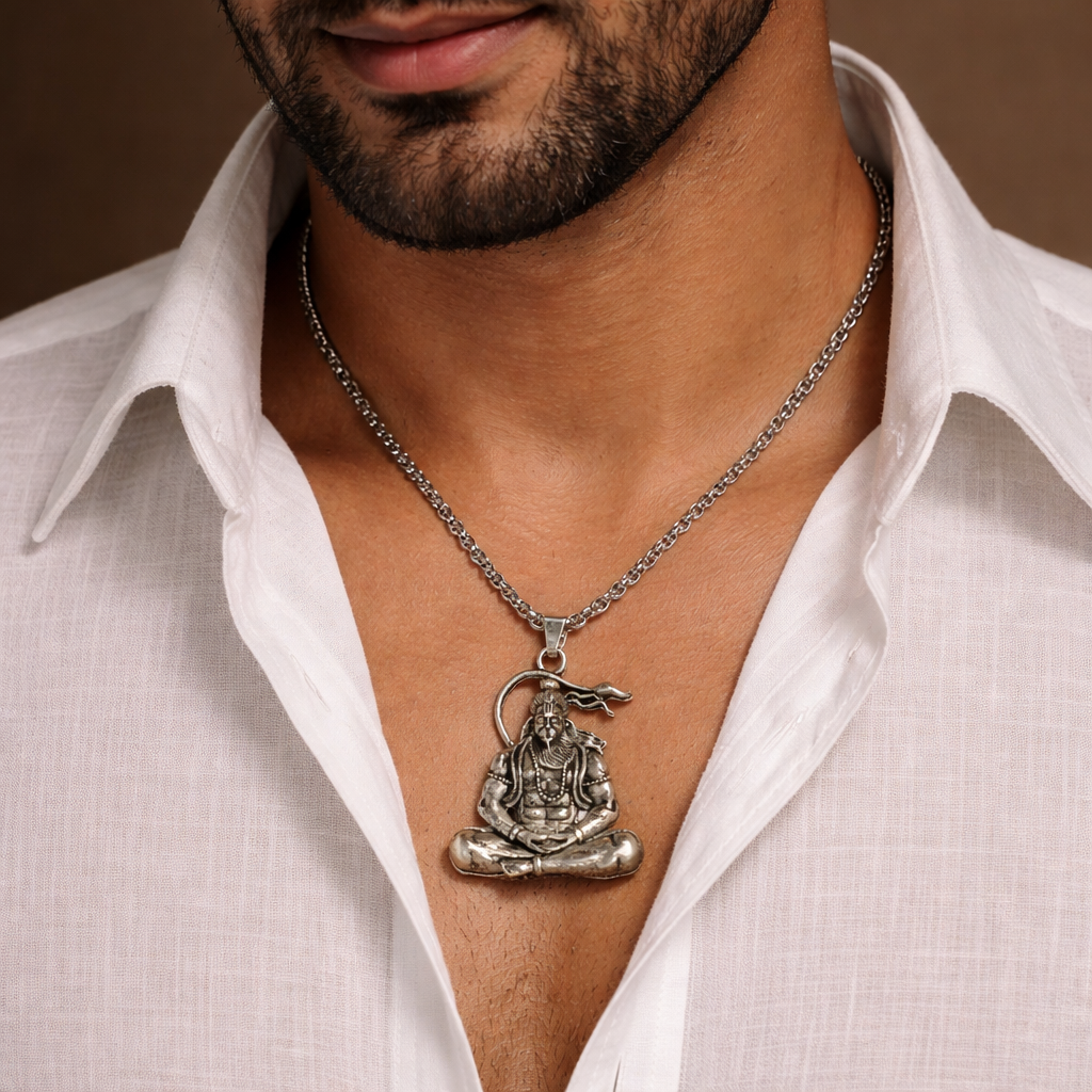 Man wearing a white shirt with a silver necklace featuring a Buddha pendant.