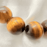 Close-up of tiger eye beads on a white fabric background