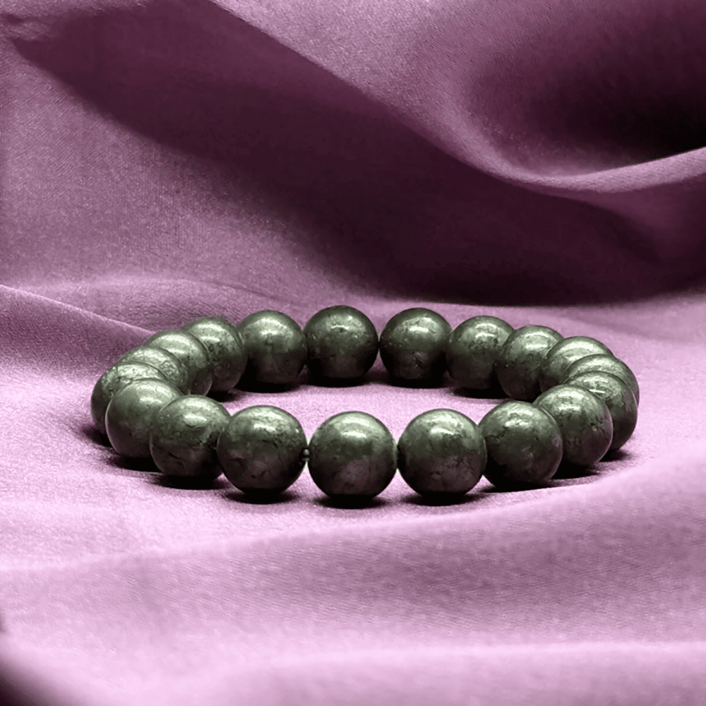 Green beaded bracelet on a purple fabric background