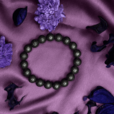 Green beaded bracelet on a purple fabric background.