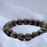Gray beaded bracelet on a white fabric background