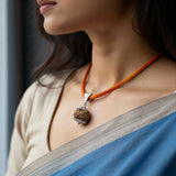 Woman wearing an orange necklace with a silver pendant