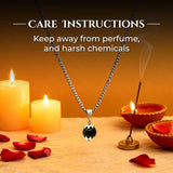 Necklace with a black and white pendant on a wooden surface with candles.