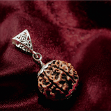Silver pendant with a brown stone on a red fabric background
