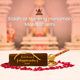 Siddh at Nursing Hanuman Mandir, Delhi with a wooden plaque.