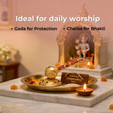 Decorative setup with a Gada, Chalisa, and lit candle on a marble surface.