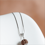 Silver necklace with a brown pendant on a white surface