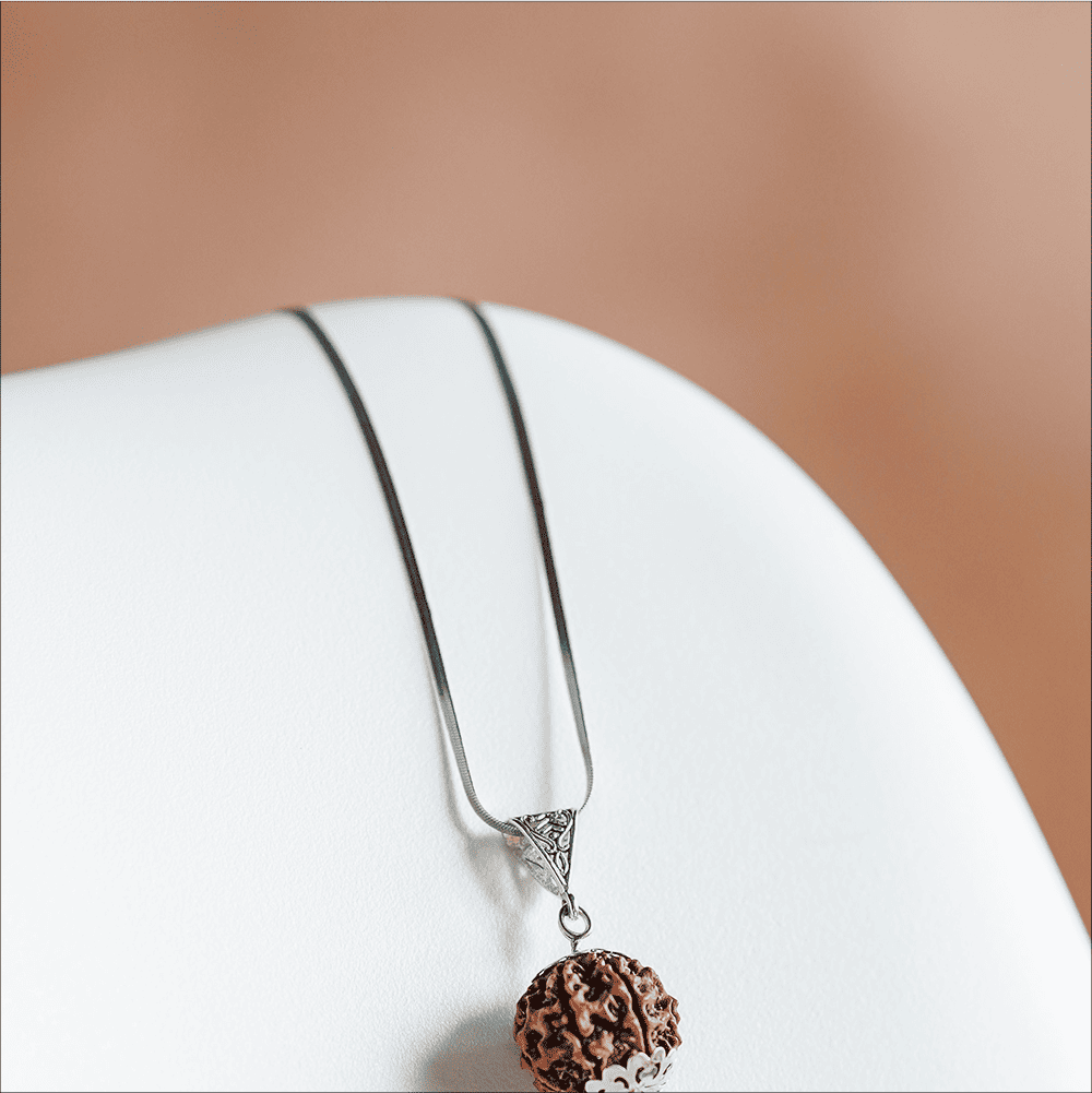 Silver necklace with a brown pendant on a white surface