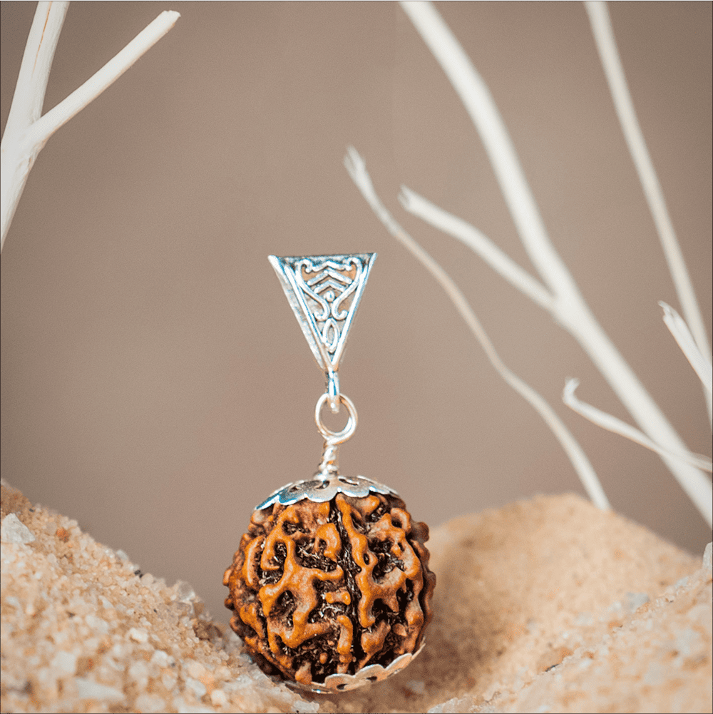 Silver pendant with a textured brown bead on a neutral background