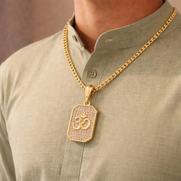 Gold necklace with a pendant featuring symbols, worn by a person in a light green shirt.